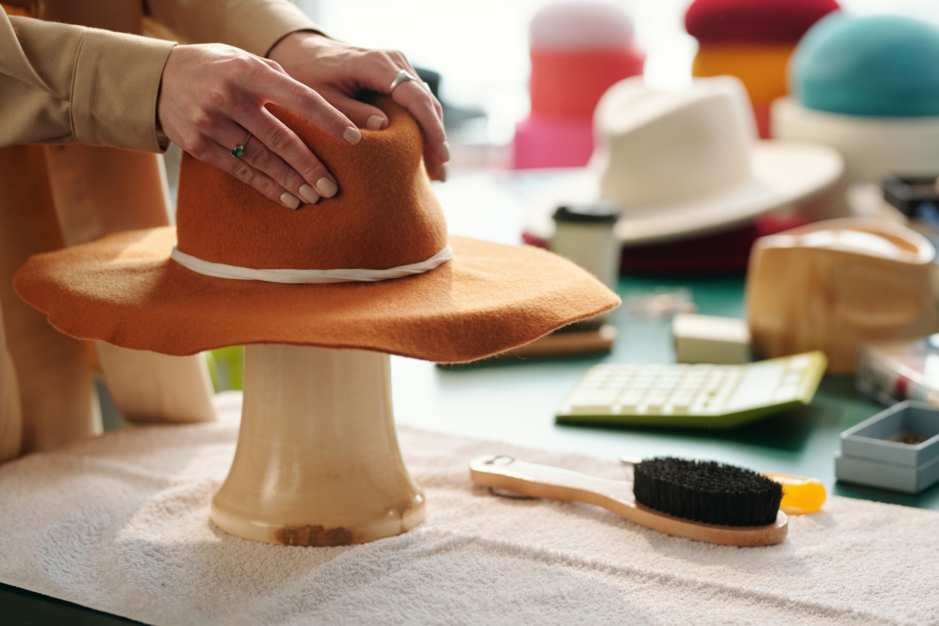 Hands of young craftswoman forming shape of brown felt hat